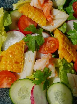 Vibrant salad featuring shrimp, corn, cucumbers, cherry tomatoes, and parsley, showcasing freshness.
