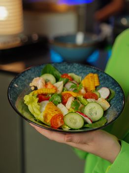 A colorful salad featuring shrimp, corn, cucumber, and tomatoes on a stylish plate. Perfect for healthy meal inspiration.