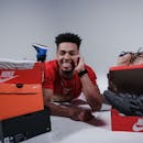 一个快乐的男人躺在各式运动鞋盒之间，展示着他的收藏