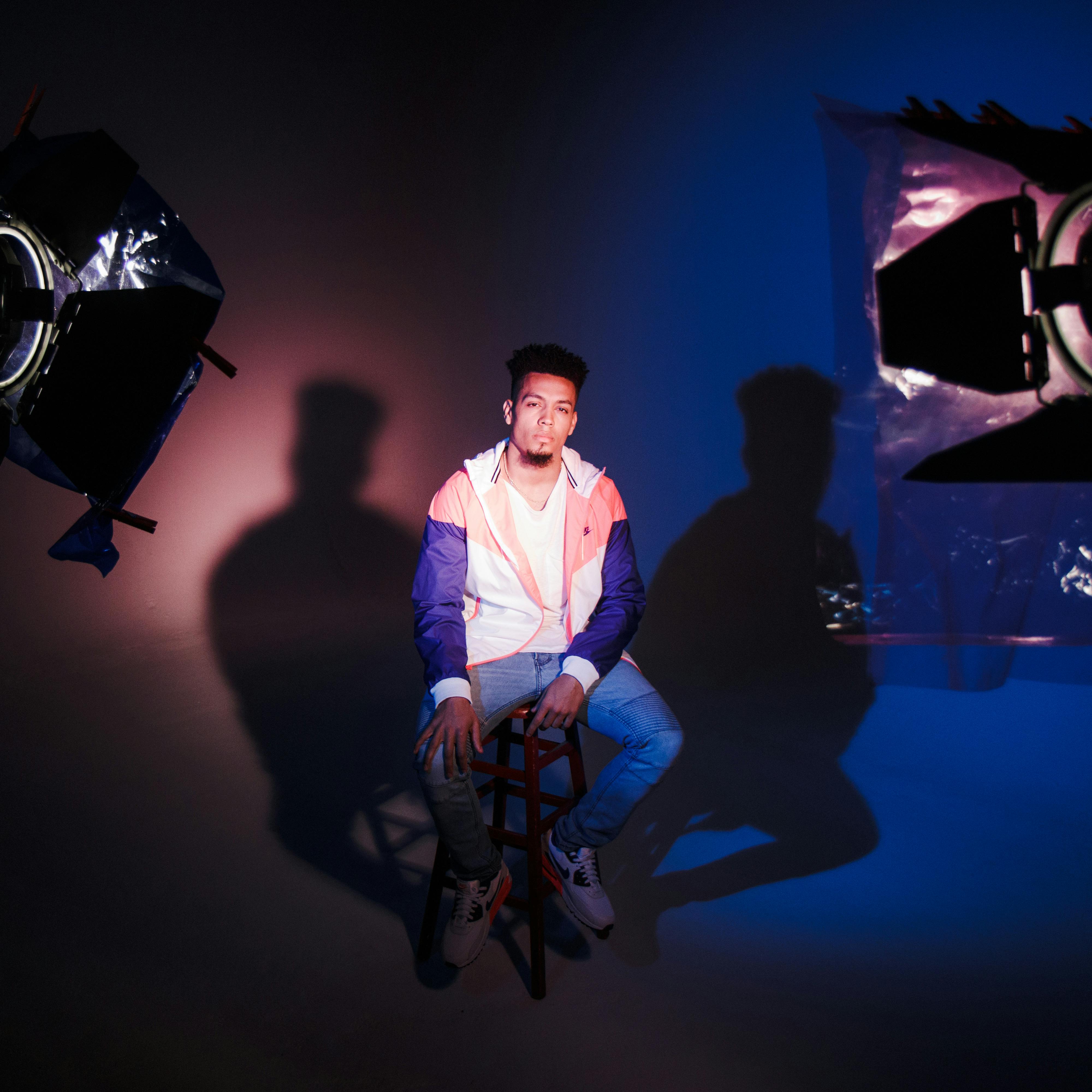 在一间灯光和阴影极具戏剧性的工作室里，一位时尚男士正在拍摄时尚照片