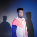 在蓝色工作室灯光下，时尚男模特穿着彩色夹克摆姿势