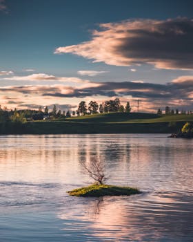 挪威索伦桑湖景色如田园诗般，郁郁葱葱的绿意在缤纷的日落天空下倒映水中