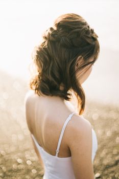 一位梳着辫子、身穿白色连衣裙的女士，正享受着海滩的宁静氛围
