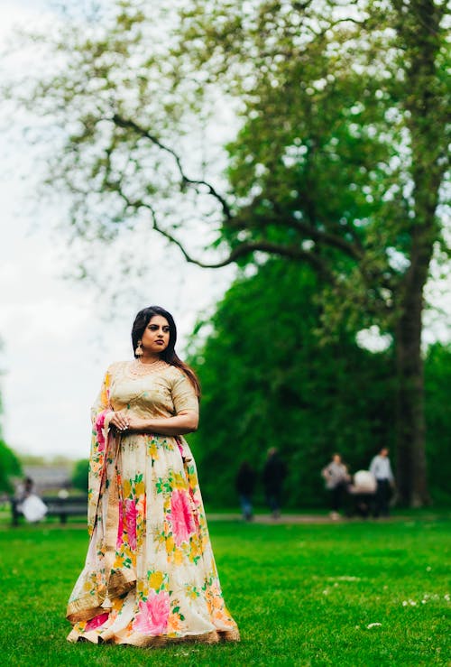 A woman in a floral lehenga poses in the park