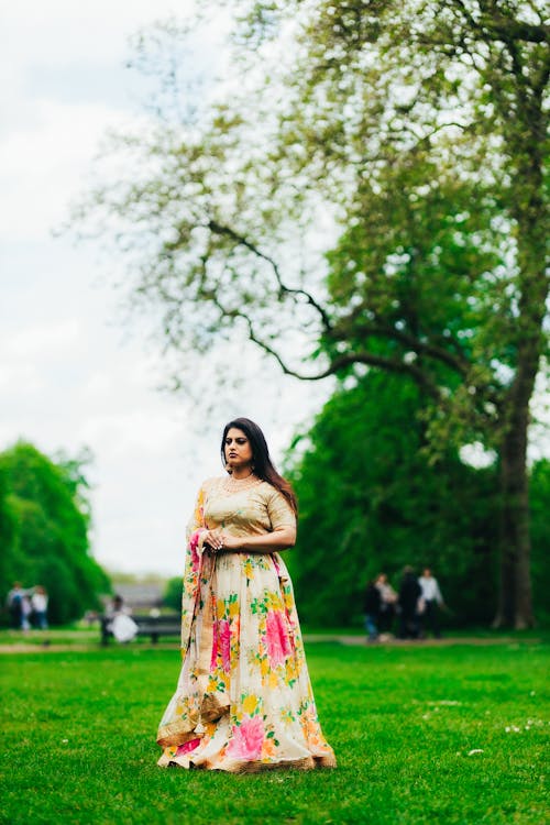 A woman in a floral dress stands in the grass