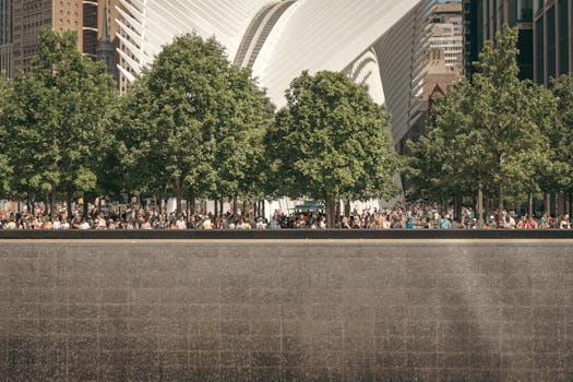 Crowds gather amidst trees by the World Trade Center Station, New York City, capturing the modern architecture by Santiago Calatrava.