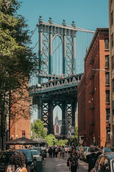 View of Manhattan Bridge framed by streets of Brooklyn, capturing urban life on a sunny day.