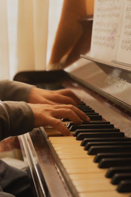 Hands skillfully play piano keys in warm natural light, creating a serene musical ambiance.