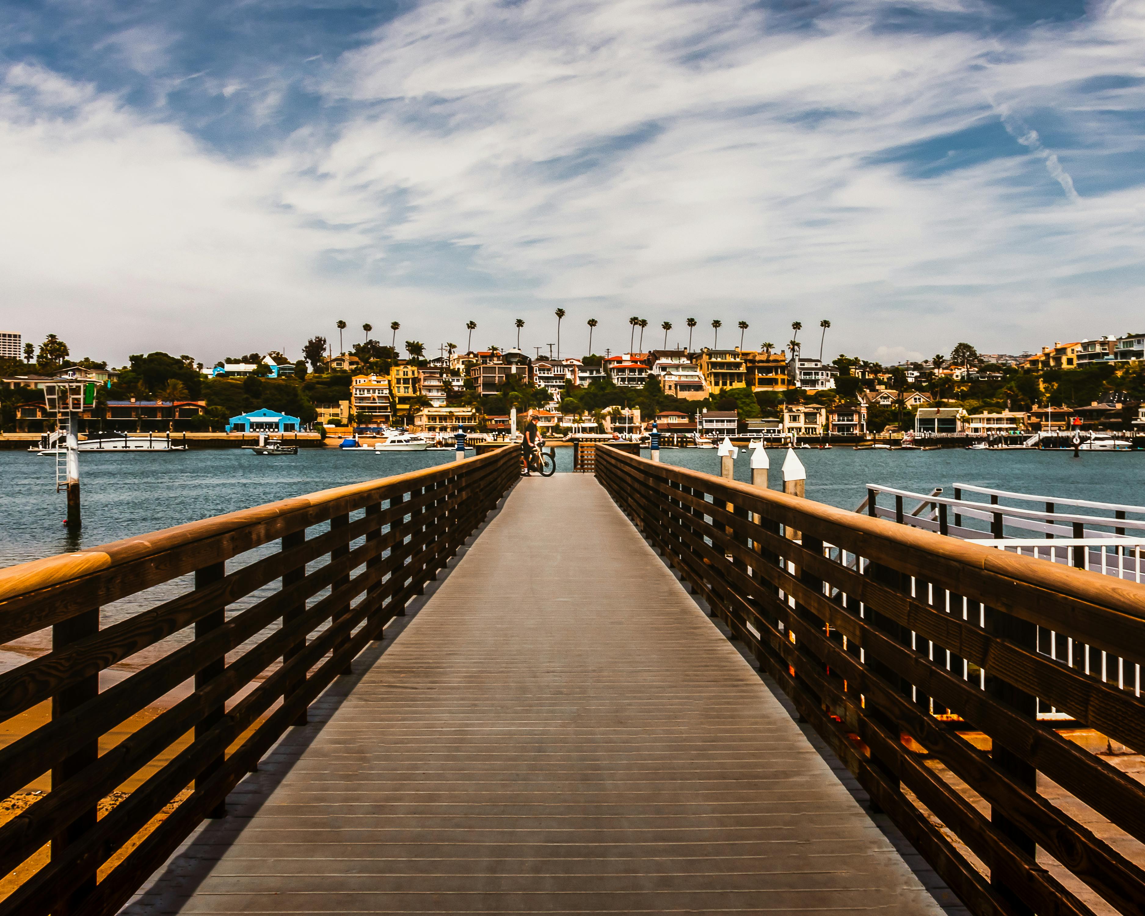从木板路上俯瞰，水面映衬着充满活力的城市景观，天空部分多云