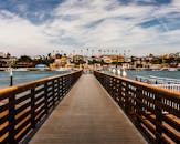 从木板路上俯瞰，水面映衬着充满活力的城市景观，天空部分多云