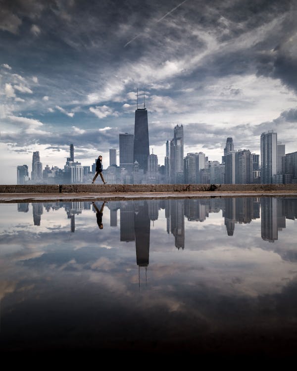 Woman Walking on Dike in Bay Overlooking City Buildings