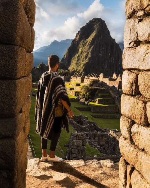 Free A man in traditional clothing overlooks the ancient ruins of Machu Picchu during daytime. Stock Photo