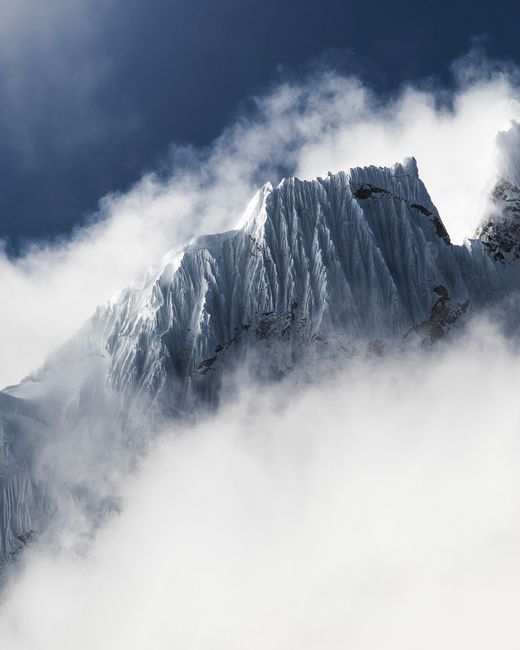 Breathtaking view of a snow-capped mountain peak rising through the misty clouds on a winter day.