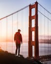 日落时分，一名身穿红色夹克的男子站在旧金山迷人的金门大桥旁