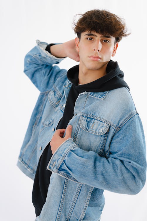 A young man in a denim jacket posing for a photo