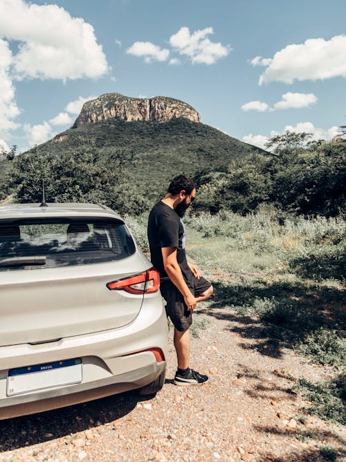 A man standing next to a car in the mountains