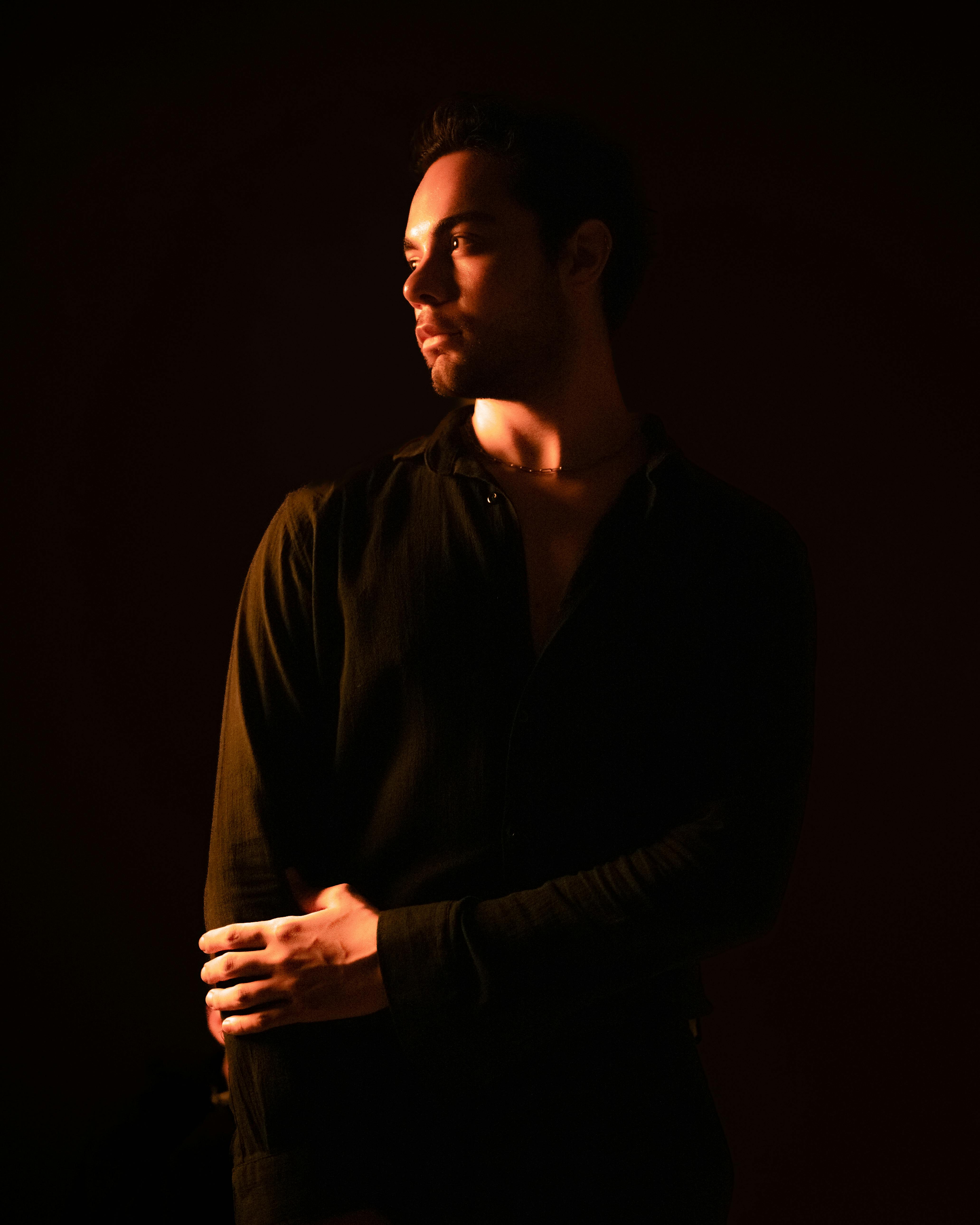 A contemplative man poses in warm, dramatic lighting, creating a serene atmosphere.
