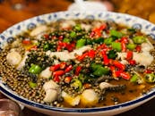 一道充满活力、辛辣的中国鱼菜，盛在装饰碗中，配以红绿辣椒