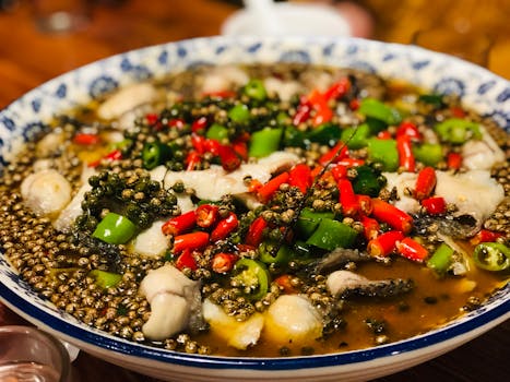 一道充满活力、辛辣的中国鱼菜，盛在装饰碗中，配以红绿辣椒