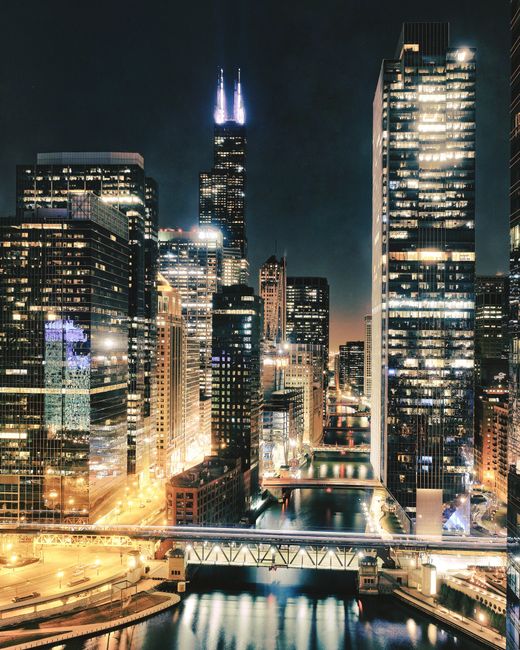 Capture of Chicago's urban skyline at night, showcasing illuminated skyscrapers along the river.