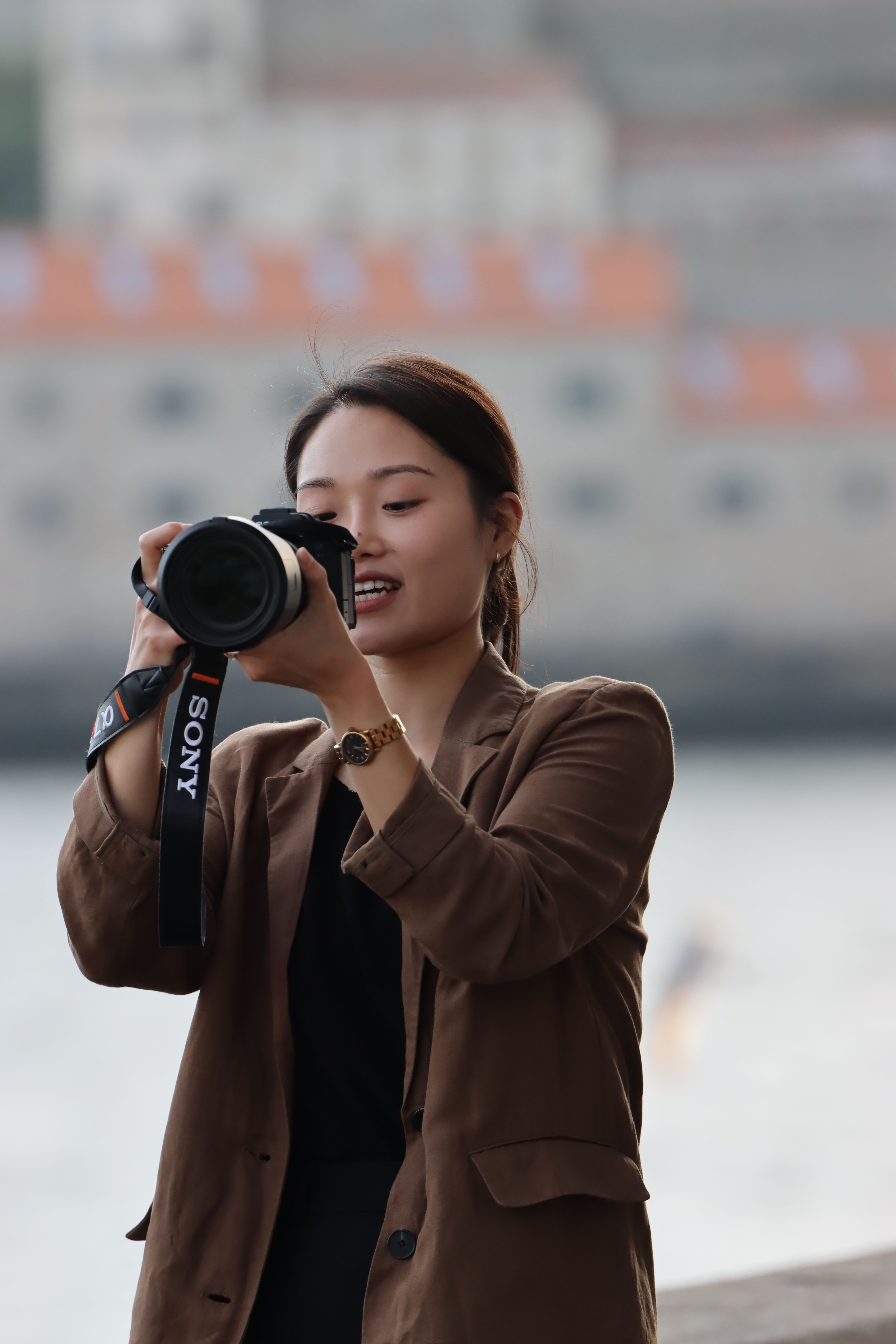 A photographer in Porto skillfully captures cityscapes with a DSLR camera beside the river.