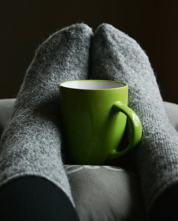 Green Ceramic Mug on Person's Feet