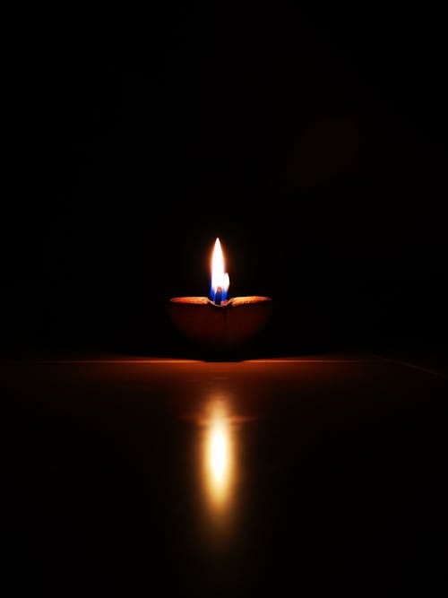 Free A lit candle on a table in the dark Stock Photo