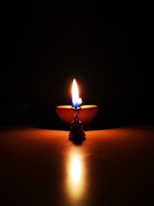 Free A lit candle on a table in the dark Stock Photo