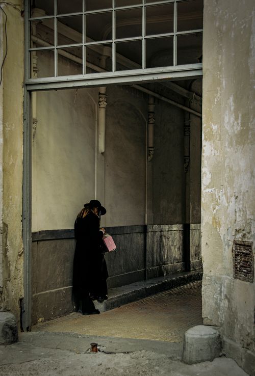 Free A woman stands pensively in a Lviv alley entrance, adding intrigue and mood to the urban scene. Stock Photo