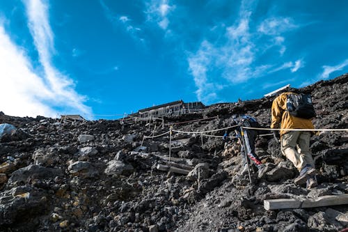 People Walking Up the Side of a Rocky Mountain Under Blue Sky