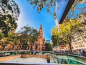 悉尼标志性的钟楼生机勃勃，四周环绕着郁郁葱葱的绿植和城市建筑