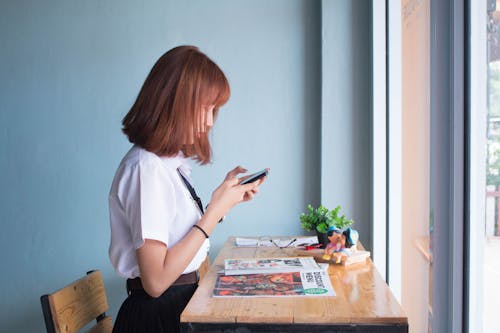 女人在桌子旁边使用智能手机