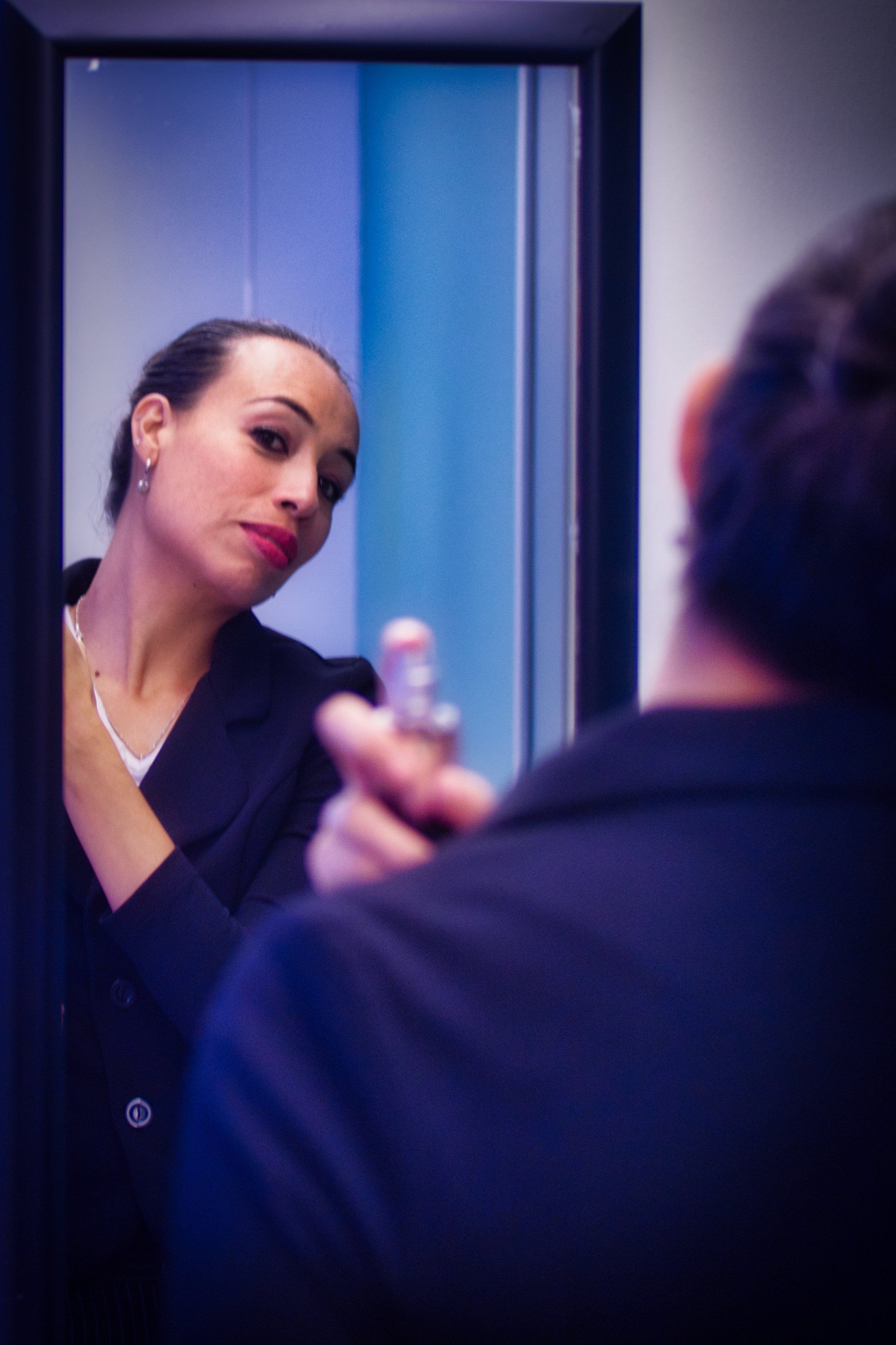 Elegant woman applying luxury perfume in front of mirror getting ready
