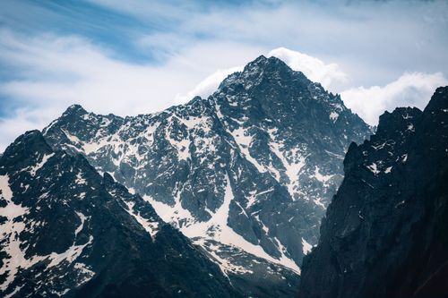 Free Stunning landscape of rugged, snowy mountains under a dramatic cloudy sky, perfect for nature enthusiasts. Stock Photo
