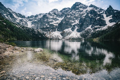 Foto profissional grátis de colinas, corrente, lago