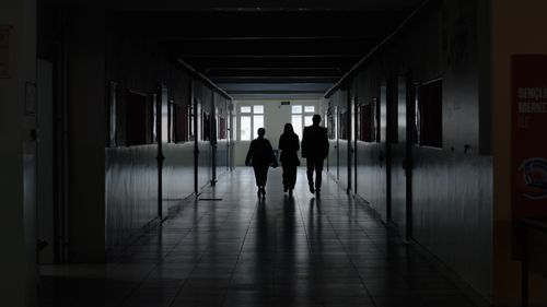 Free Three people walk through a dimly lit corridor, creating a mysterious atmosphere. Stock Photo