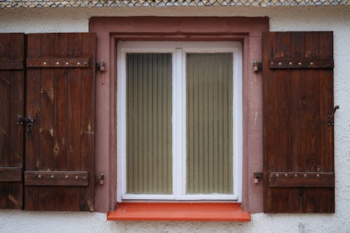 A window with wooden shutters and orange trim