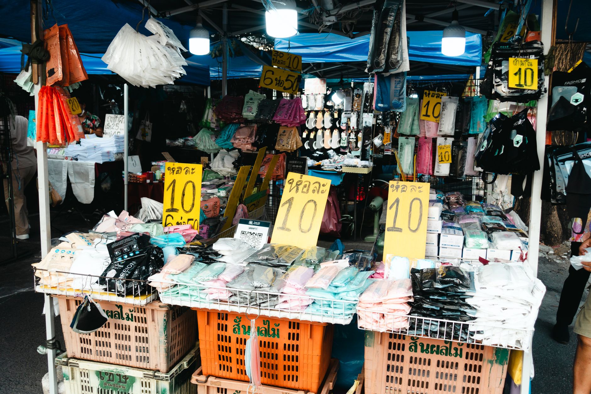 Colorful street market with clothing stalls and sale signs, vibrant and bustling.