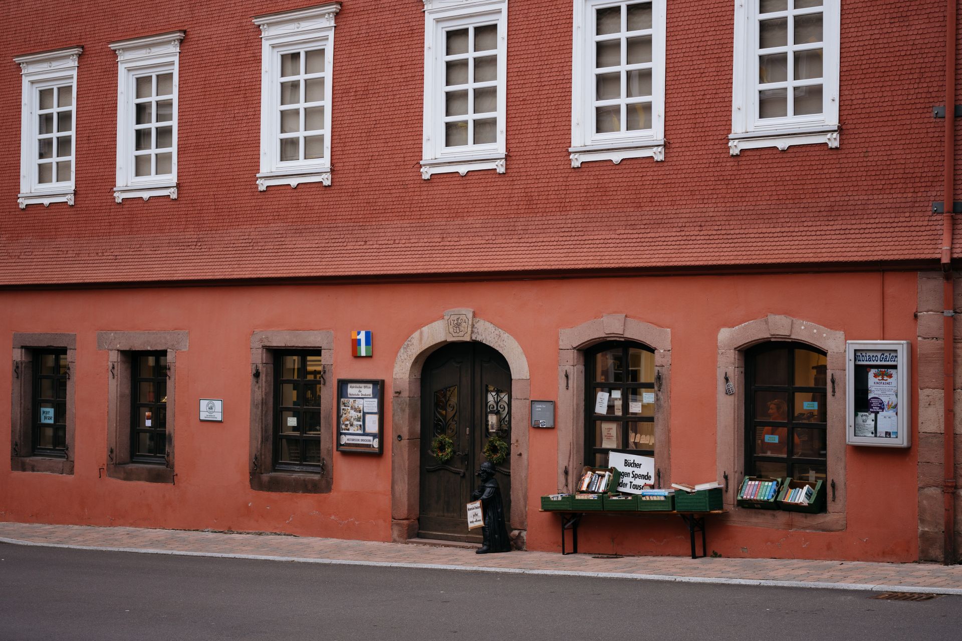 A quaint second-hand bookstore with books displayed outside on city street.