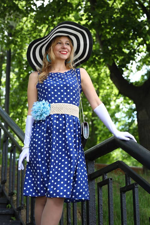모자와 파란색 폴카 도트 드레스를 입고 여자