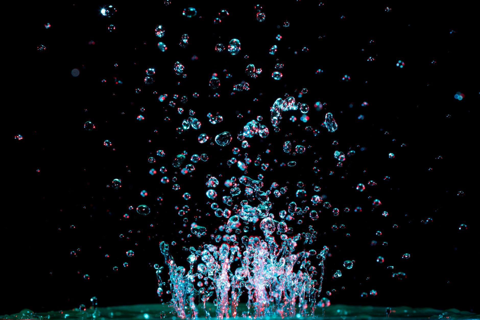 Captivating close-up of water droplets captured mid-splash against a dark background, showcasing fluid dynamics.