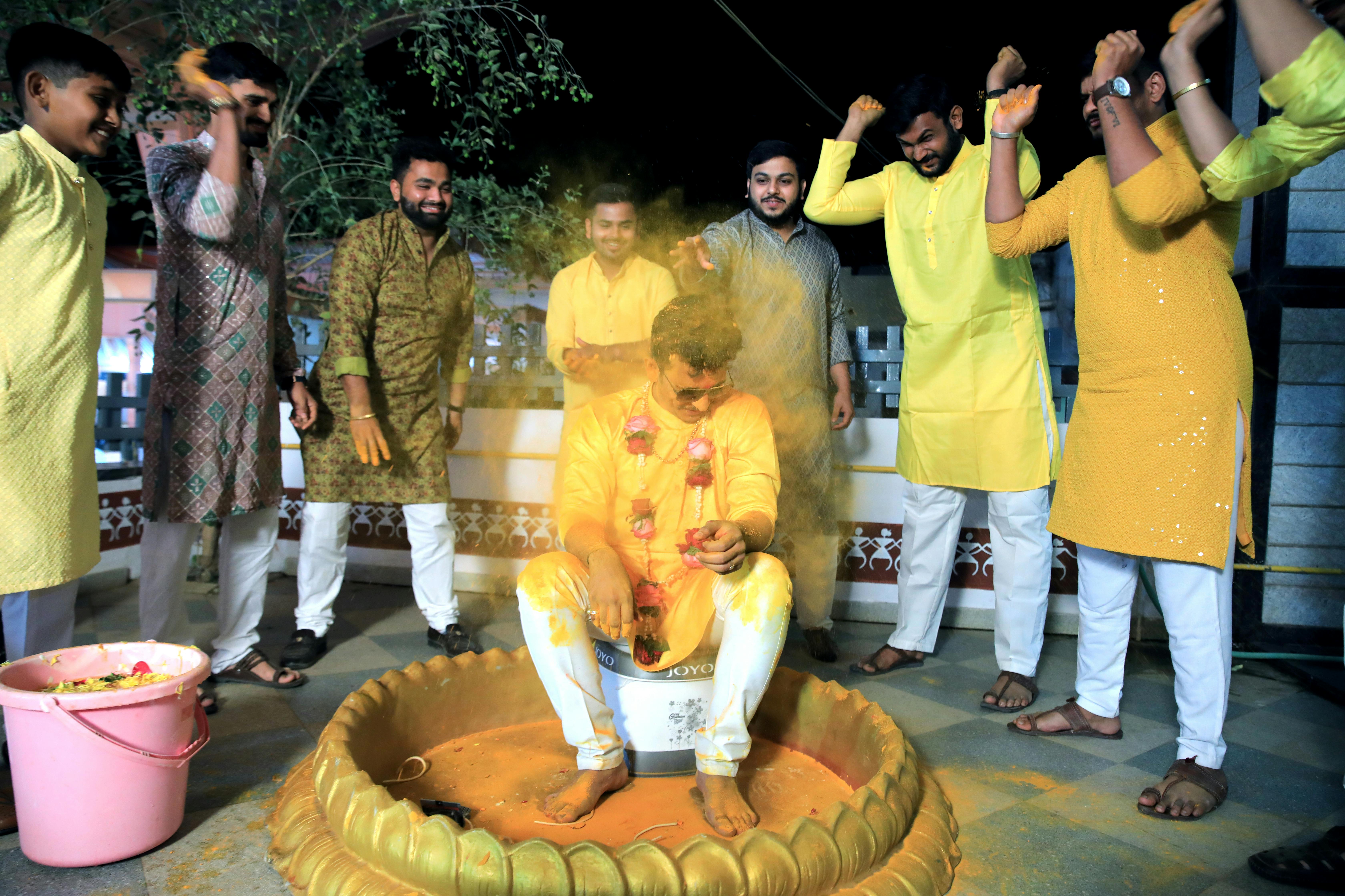 group of friends showering a man with orange holi powder