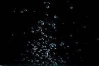 这张在暗色背景下拍摄的水滴微距镜头令人惊叹，完美展现了流动的韵律与自然之美