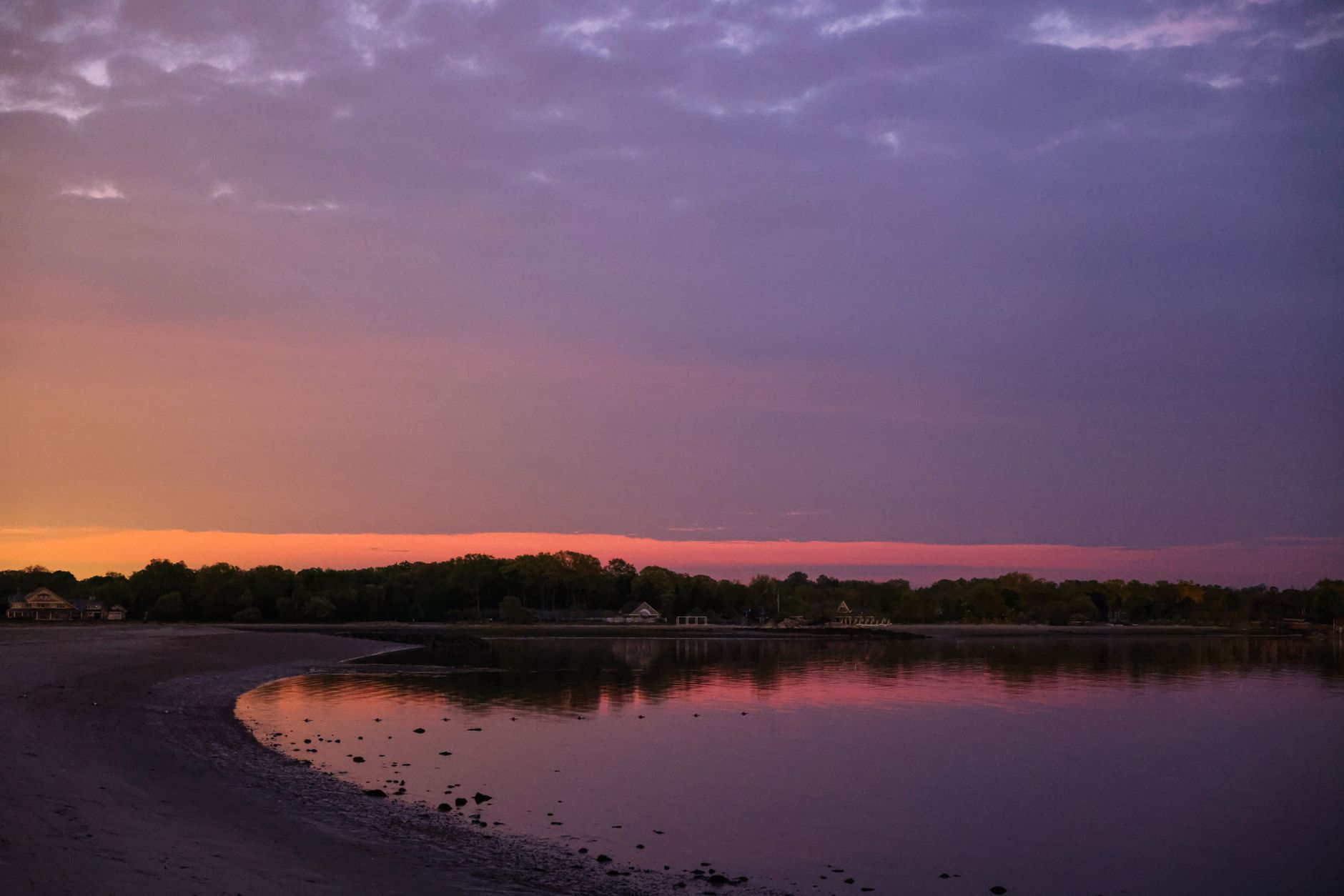 Peaceful twilight scene of a beach in Stamford, CT, capturing vibrant sunset hues over tranquil waters.