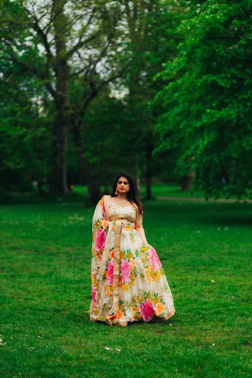 A woman in a floral dress stands in the grass