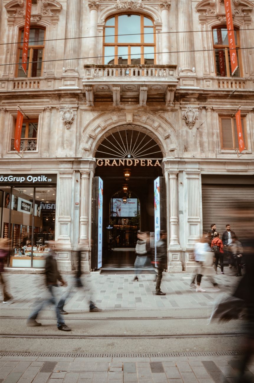 Long exposure shot capturing motion in front of Grand Pera in Istanbul, blending historic architecture with modern urban life