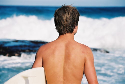Free Man Carrying White Surfboard Stock Photo