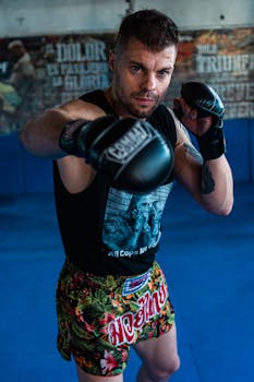 Athletic man in boxing stance with gloves in an indoor gym setting.