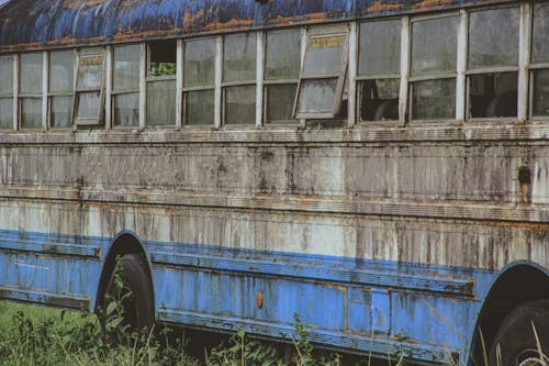 An old rusted bus sitting in a field