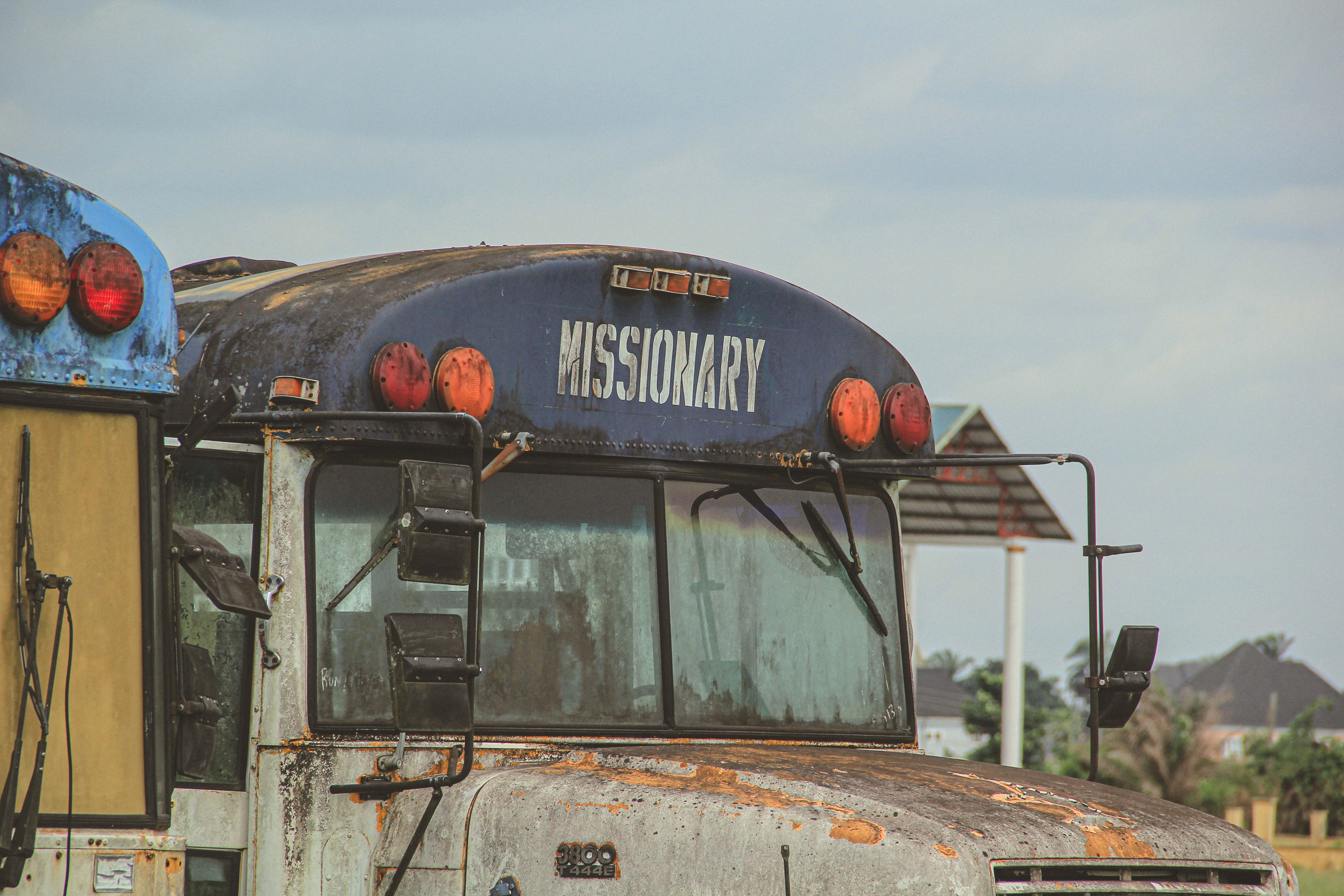Close-up of a weathered missionary bus in an outdoor setting with visible rust.